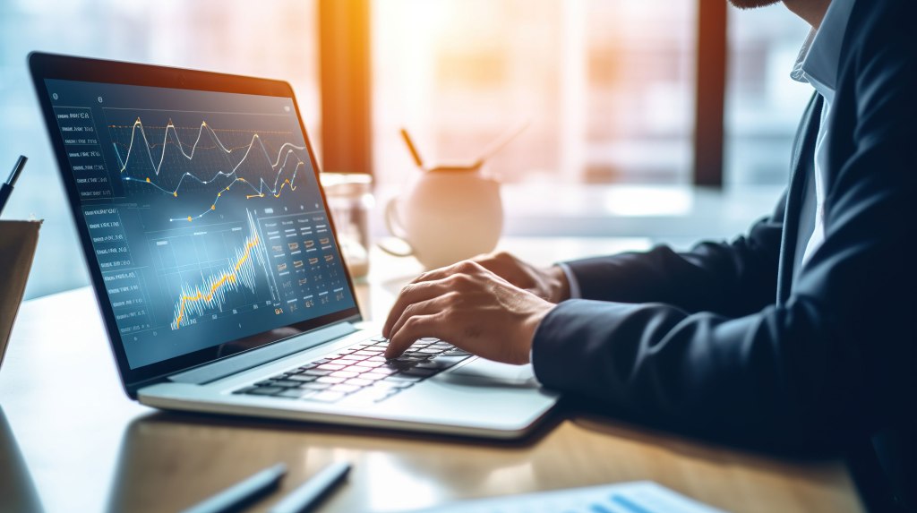 Businessperson typing on laptop with stock performance chart