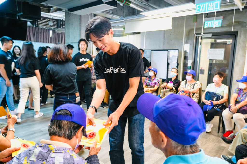 Giving Back: Jefferies volunteers share giveaways with an assembled group of people
