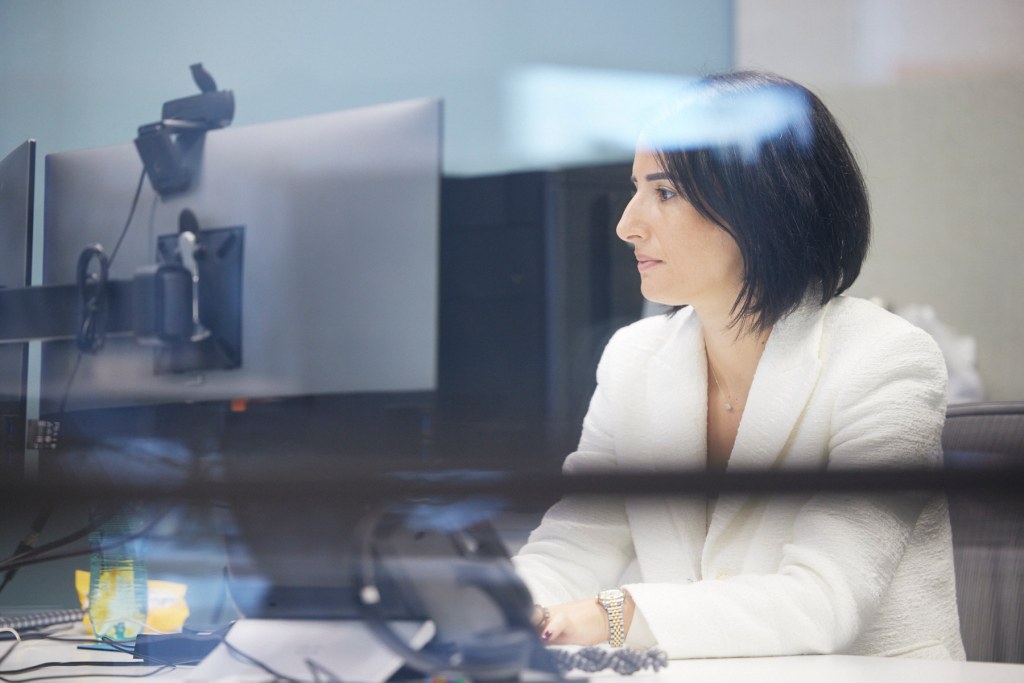 About: Focused professional at desk facing her computer