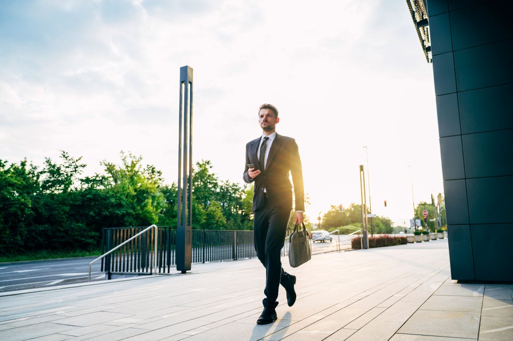 Investor email alerts: Serious young businessman arriving at work in morning