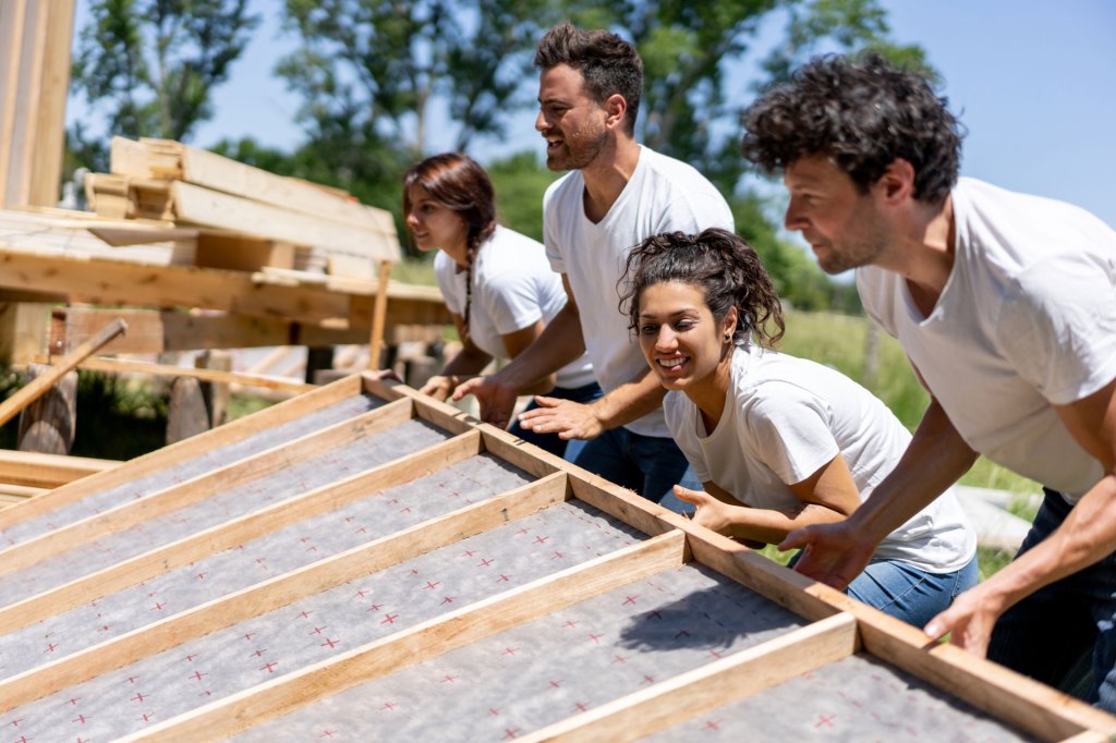 Diversity Equity and Inclusion: Community Engagement - Team of volunteers lifts framed wall of new home